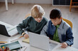 © Seventyfour - Two young multiethnic male students pairing up while studying on laptop during collaborative task at school