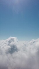 Wall Mural - drone flies over foggy and fluffy clouds. aerial vertical view. blue sky sun and sea fog. abstract a