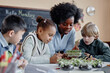 © Seventyfour - Multiethnic group of primary school kids discovering growth of plants looking at microgreen sprouts during biology lesson
