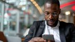 © svastix - A focused businessman in a modern airport lounge, dressed in a suit, is checking his smartphone, reflecting today's interconnected and fast-paced professional environment.