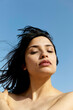 © Connect Images - A serene woman with dark hair enjoys a calm moment under a clear blue sky.