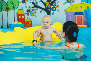 Wall Mural - Little boy in the pool. A baby learns to swim with a coach in the pool. Swimming courses for small children. Swimming pool for children