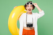 © ViDi Studio - Traveler surprised shocked happy woman wear casual clothes glasses hold rubber ring isolated on plain green background. Tourist travel abroad in free spare time rest getaway. Air flight trip concept.