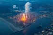 © Thomas - Aerial image of steel plant, factory, refinery with massive flame from chimney. Generating, producing steel and metal from coal and iron ore in IJmuiden Netherlands during evening alongside North Sea