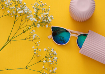 Canvas Print - Sunglasses in a plastic case on a yellow background with flowers