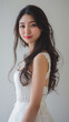 © CreativeInside - Beautiful Japanese woman with long hair wearing makeup and smiling while dressed in a white dress with a simple background.