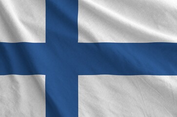 Wall Mural - Finland flag depicted on folded wavy fabric of old cloth close up