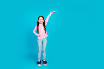 Sticker - Full size photo of adorable small girl with ponytails dressed striped shirt measure height empty space isolated on blue color background