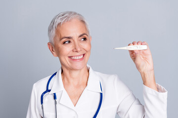 Sticker - Photo of aged lady professional doctor thermometer look empty space wear white coat isolated on grey color background