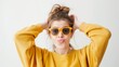 © Pro Hi-Res - Young woman wearing a yellow sweatshirt and yellow sunglasses making a funny face and looking into the distance, against a white background.