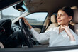 © SHOTPRIME STUDIO - Smiling woman sitting in the driver's seat of a car with one hand on the steering wheel, embodying confidence and joy in a driving experience
