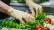 © Shaheen - a food handler wearing gloves while preparing a fresh salad, ensuring hygiene and safety.