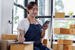© David - Entrepreneurs small business SME independent asian woman work at home use calculator, phone and laptop for commercial checking. online marketing packing boxes SME sellers concept, E, sme online sales
