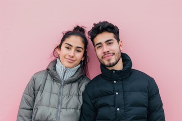 Wall Mural - Portrait of a tender latino couple in their 20s dressed in a water-resistant gilet isolated on solid pastel color wall