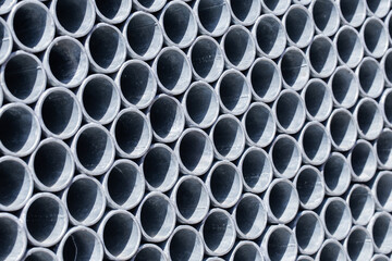 Metal pipes stacked one on top of another background. Forming a regular structure texture. Side view of the pipes. Blue industrial steel pattern. Grunte metalic backdrop.