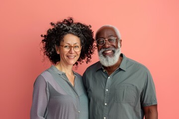 Wall Mural - Portrait of a glad mixed race couple in their 60s wearing a simple cotton shirt isolated on solid pastel color wall