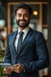 © VISUAL BACKGROUND - A smiling man in a suit holding a tablet.