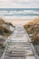 Canvas Print - A wooden boardwalk leads to the ocean. The beach is sandy and the water is calm. The sky is blue and there are no clouds