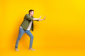 Photo of funny nice man wear stylish khaki clothes push empty space isolated on vivid yellow color background