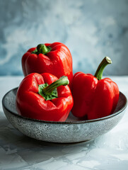 Wall Mural - Three red bell peppers in a bowl with a textured background