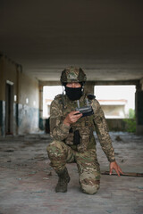 Wall Mural - Military mission. Soldier in uniform with drone controller inside abandoned building