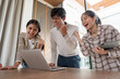 © Natee Meepian - Group of Excited Student Celebrating Success Together in a Modern Study Space with a Laptop