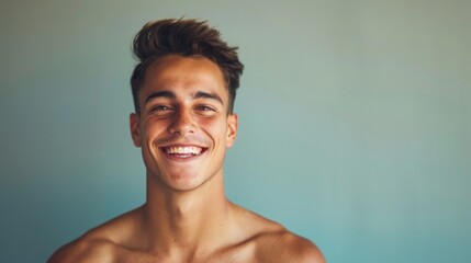 A young man with short brown hair smiles against a light blue background.