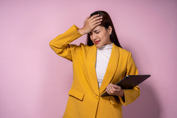 Wall Mural - A woman in a yellow jacket is holding a tablet and appears to be in pain