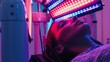 © Prostock-studio - A woman lies on a table with her eyes closed, receiving red light therapy. The red light panel is positioned directly above her head.