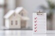 © KanitChurem - Home inspection checklist with red check marks on clipboard, miniature house model in the background. Real estate and home buying concept.