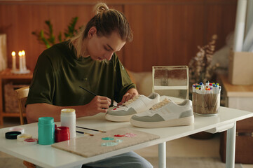 Designer making handmade, he sitting at his workplace and drawing on sneakers