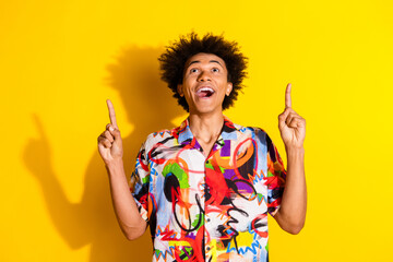 Wall Mural - Portrait of nice young man indicate fingers up empty space wear shirt isolated on vivid yellow color background