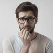 © MaryKovs - Nervous Man with Glasses Biting Nails Against Beige Background