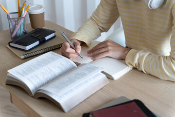 Poster - teenage woman is sitting on her home desk reading a book