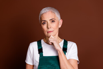 Wall Mural - Photo of smart clever lovely senior woman wear uniform arm touch chin isolated on brown color background