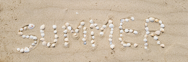 Summer beach concept with the word 'SUMMER' spelled out using seashells on sandy beach, ideal for vacation and relaxation themes