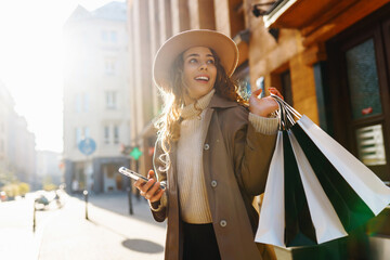 Wall Mural - Fall elegant woman carrying shopping bags walking city street. Consumerism, sale, purchases, shopping, lifestyle concept.