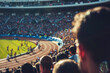 © eshana_blue - Crowd is enjoying a sunny day at the stadium watching athletes running on a track