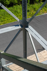 Bolted connections of steel elements of the observation tower. Construction details of galvanized steel against a grey asphalt road surphace