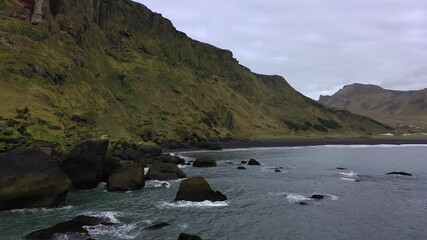 Wall Mural - Aerial Drone footage of waves crashing on the rocks and black sand beaches of Vik, in Iceland