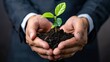 © M.IVA - Man in business suit carefully holding a plant with soil in hands, symbolizing growth and investment.
