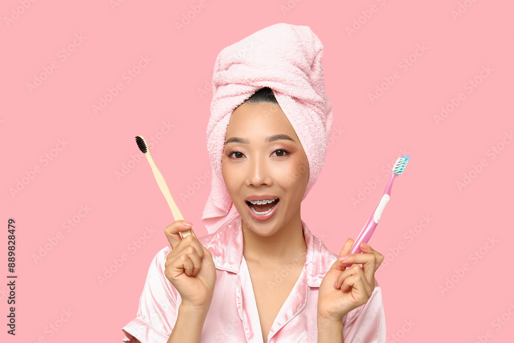 Young Asian woman with toothbrushes on pink background, closeup