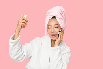 Poster - Young Asian woman with reusable cotton pad and cleanser on pink background