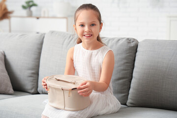 Sticker - Cute little girl with cosmetic bag sitting on sofa in living room