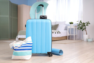 Wall Mural - Packed suitcase with camera, beach bag and yoga mat in interior of bedroom