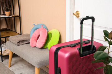 Sticker - Pink suitcase and neck pillows on bench near doorway in hall. Travel concept