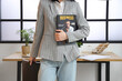 © Pixel-Shot - Young woman holding magazine near workplace in beautiful office