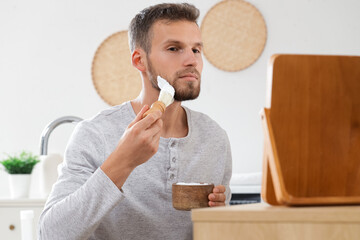 Sticker - Bearded young man applying shaving foam with brush at home