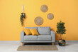 © Pixel-Shot - Cozy sofa and houseplant near orange wall in living room