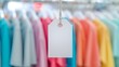 © ontsunan - Empty white tag hanging, blurred colorful shirts in the background, suggesting a clothing store or fashion retail setting.